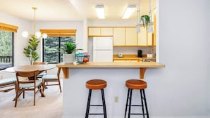 A modern kitchen with a wooden island, bar stools, and a dining area with a round table and chairs.