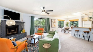 A living room with a fireplace, a sofa, a coffee table, and a dining area with a bar.