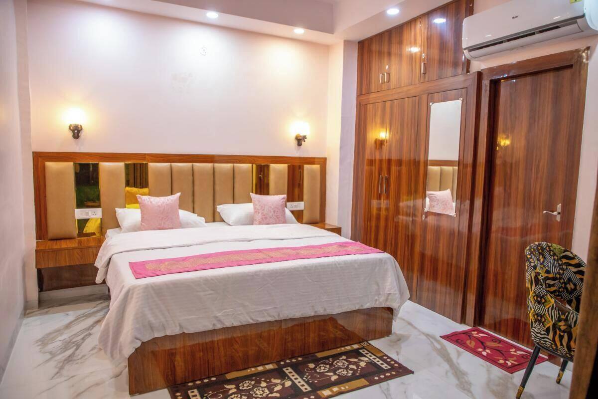 A hotel room with a large bed, wooden wardrobe, and a small chair.