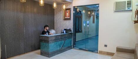 A reception area with a reception desk, a ceiling fan, and a glass door leading to a hallway.