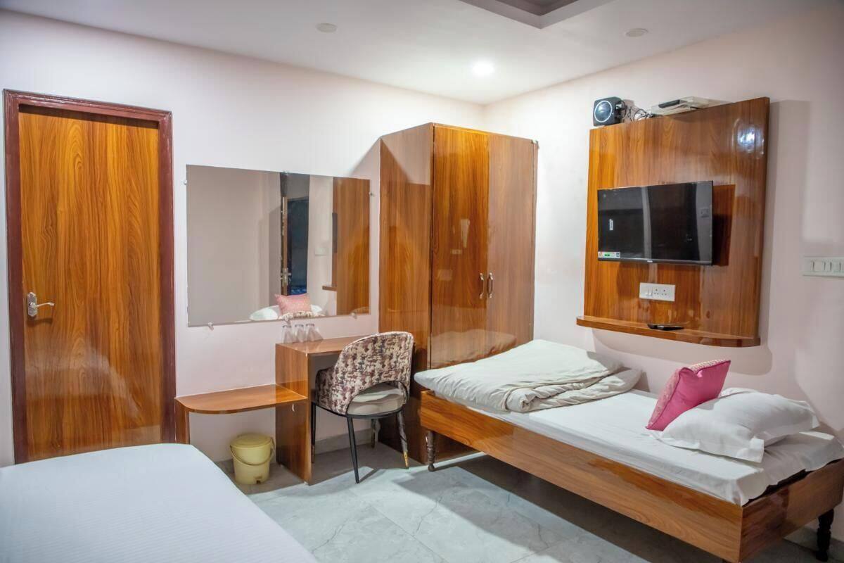 A bedroom with a bed, a desk, a chair, a wardrobe, and a TV mounted on the wall.