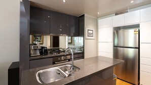 Eine moderne Küche mit Edelstahlgeräten, einem eingebauten Ofen und einem großen Kühlschrank.
