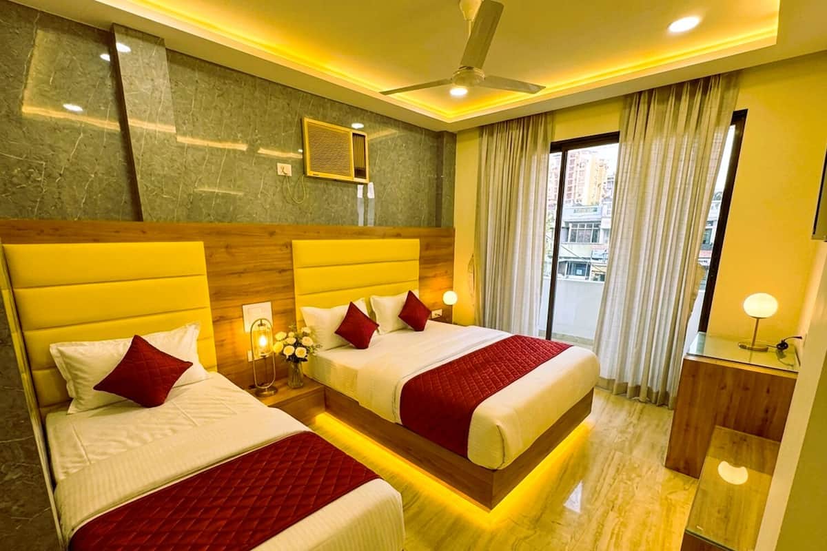 Ein Hotelzimmer mit zwei Betten, einem Deckenventilator, einem Fenster mit Vorhängen und einem Nachttisch mit Lampe.