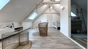 A loft bedroom with a sloped ceiling, a bed, a desk, and a chair.