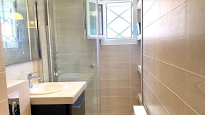 A modern bathroom with a glass shower enclosure, a sink, and a mirror.