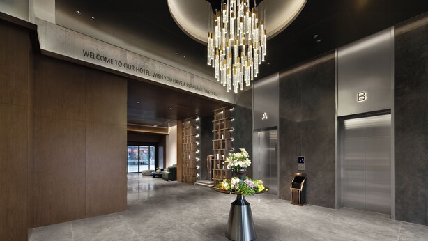 A modern hotel lobby with a welcoming sign, a chandelier, a reception desk, and an elevator. - RunhaoHOTEL (Chengdu)