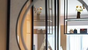 A hotel room with a mirrored wall reflecting a modern interior, a glass shelf with decorative items, and a neatly arranged table with a vase and a small plant. - RunhaoHOTEL (Chengdu)