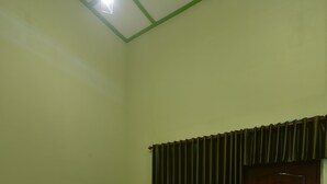A room with a bed, a door, and a curtain. - Hotel Irian Surabaya (Surabaya)