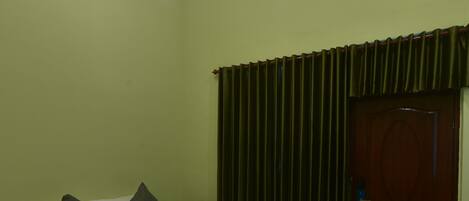 A room with a bed, a door, and a curtain.