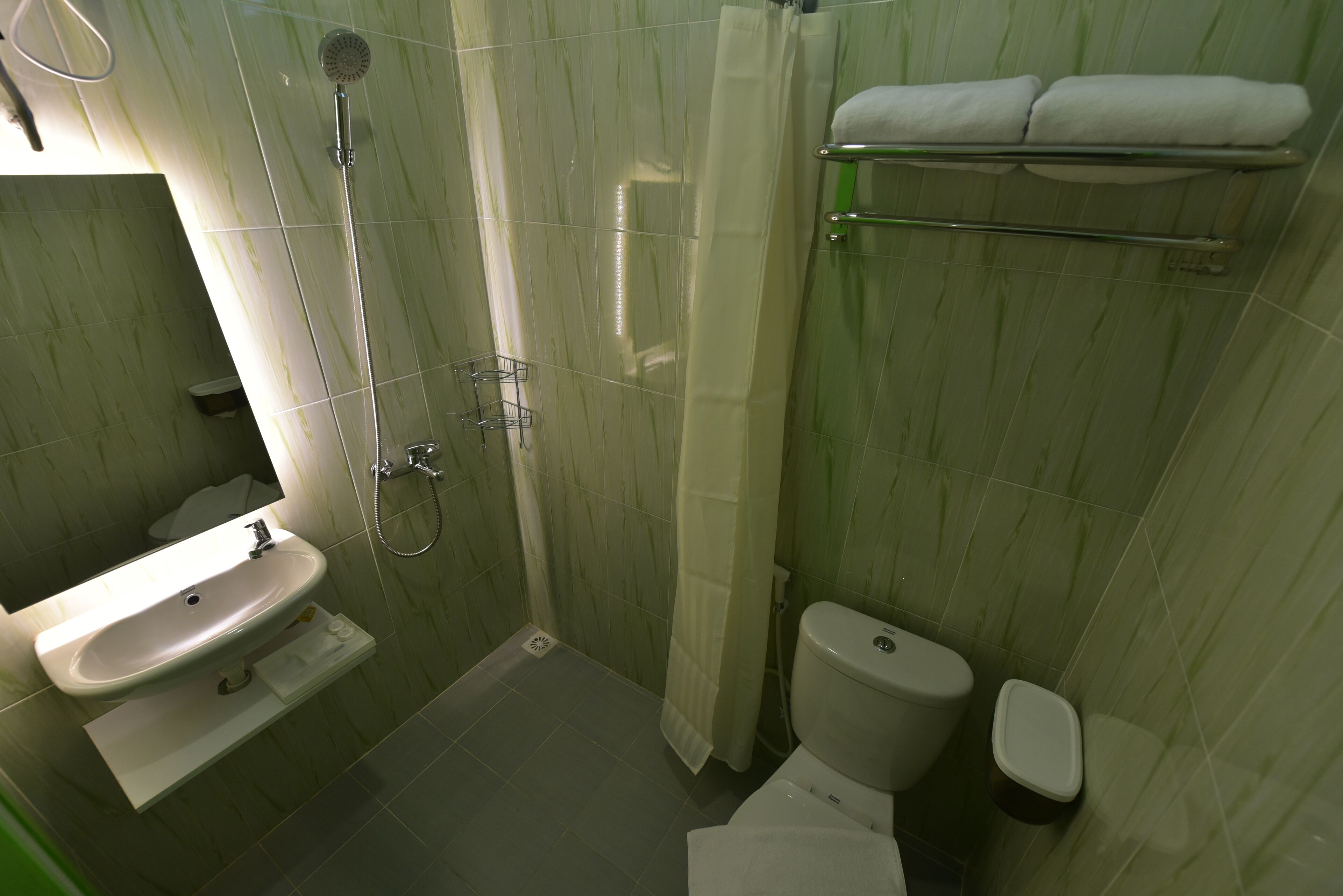 A bathroom with a sink, toilet, shower, and towel rack.