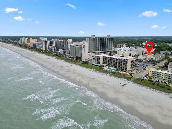 Un hôtel situé en bord de mer, composé de plusieurs bâtiments, doté d’une piscine et donnant accès à une plage.