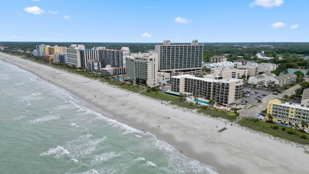 Ein Hotel an der Küste mit mehreren Gebäuden, einem Strand und einem Schwimmbad.