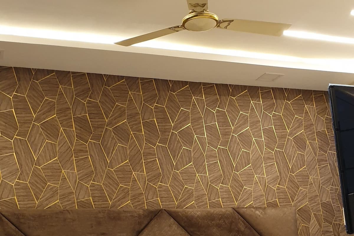 A modern bedroom with a large bed, a ceiling fan, and a geometric-patterned wall.