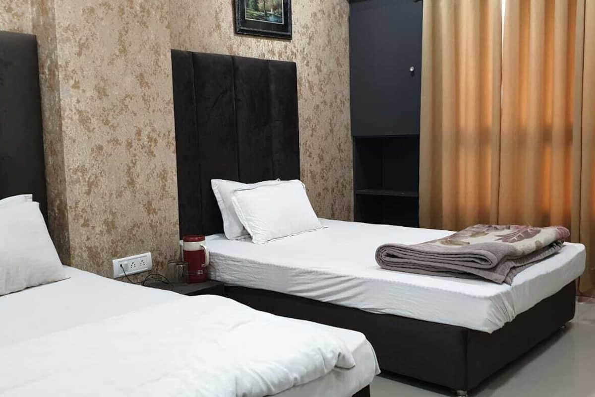 A hotel room with two beds, a coffee machine, a chair, and a wardrobe.