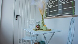 A small white table with a vase of dried flowers, a candle, and a green bottle.