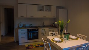 A modern kitchen with white cabinets, a dishwasher, and a dining area with a table set for two.