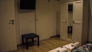 A room with a wardrobe, a small table, and a bed with towels.