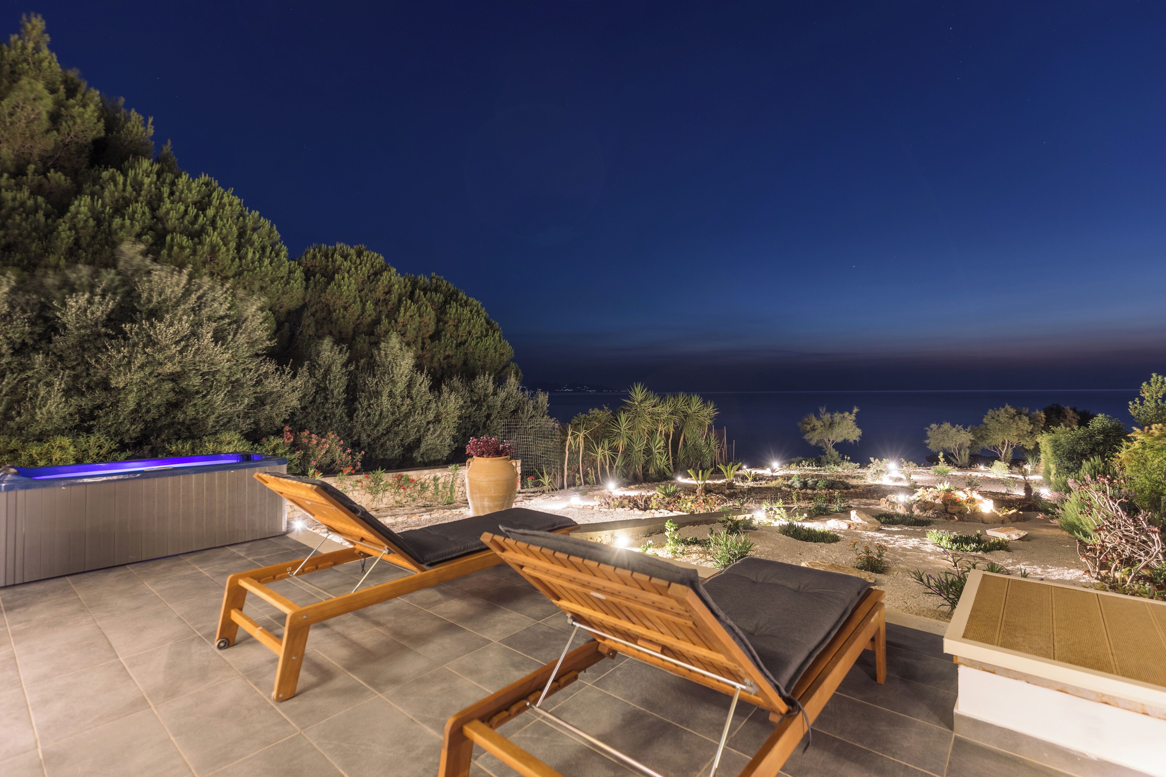 Une terrasse sur le toit, dotée de deux chaises longues en bois, d’un jacuzzi et d’un jardin aménagé offrant une vue sur la mer.