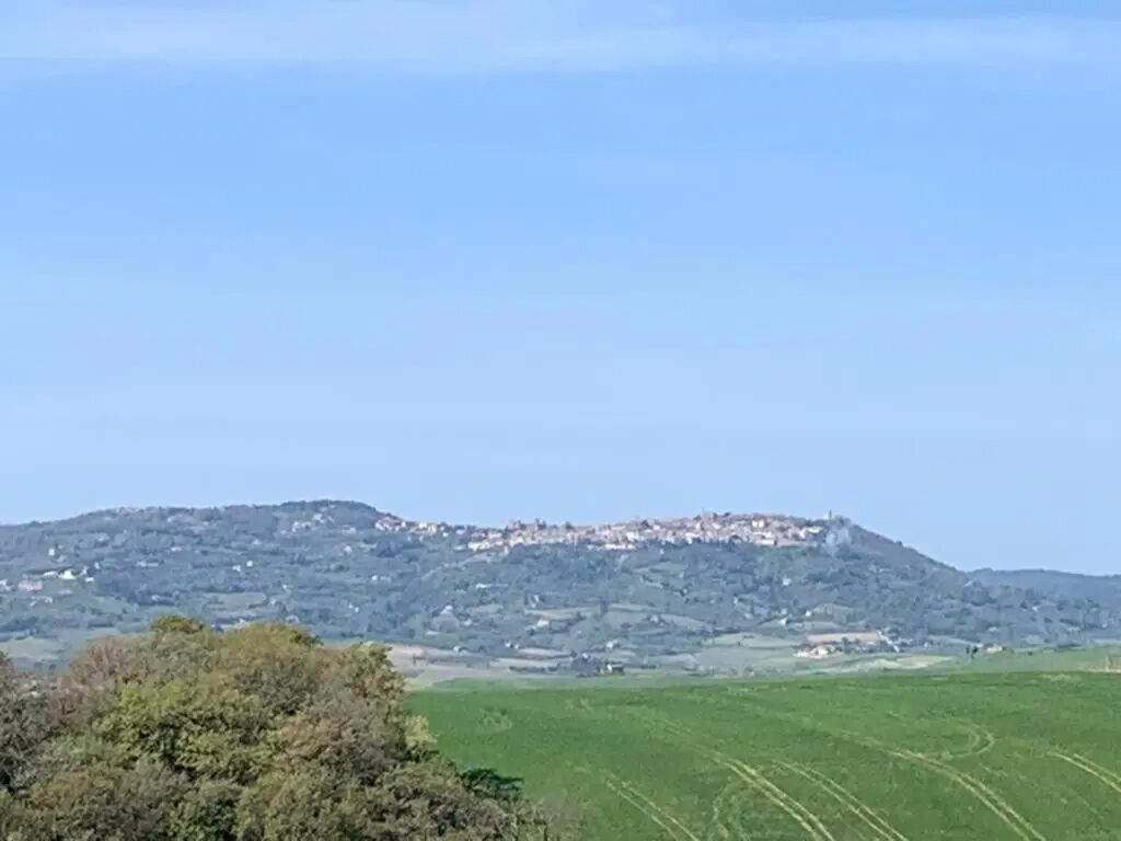 A rural landscape with a hill and scattered buildings.