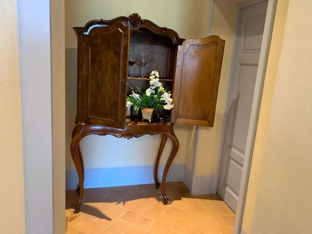 Ein Holzkabinent mit einer Vase weißer Blumen.