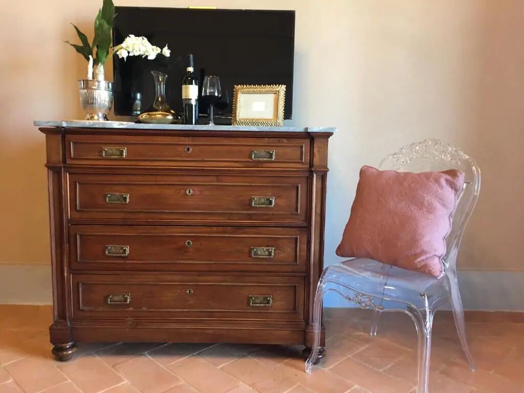 A wooden dresser with drawers and a clear chair with a cushion.
