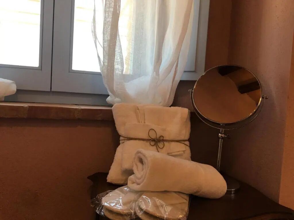 A bathroom with a window, a mirror, and towels.