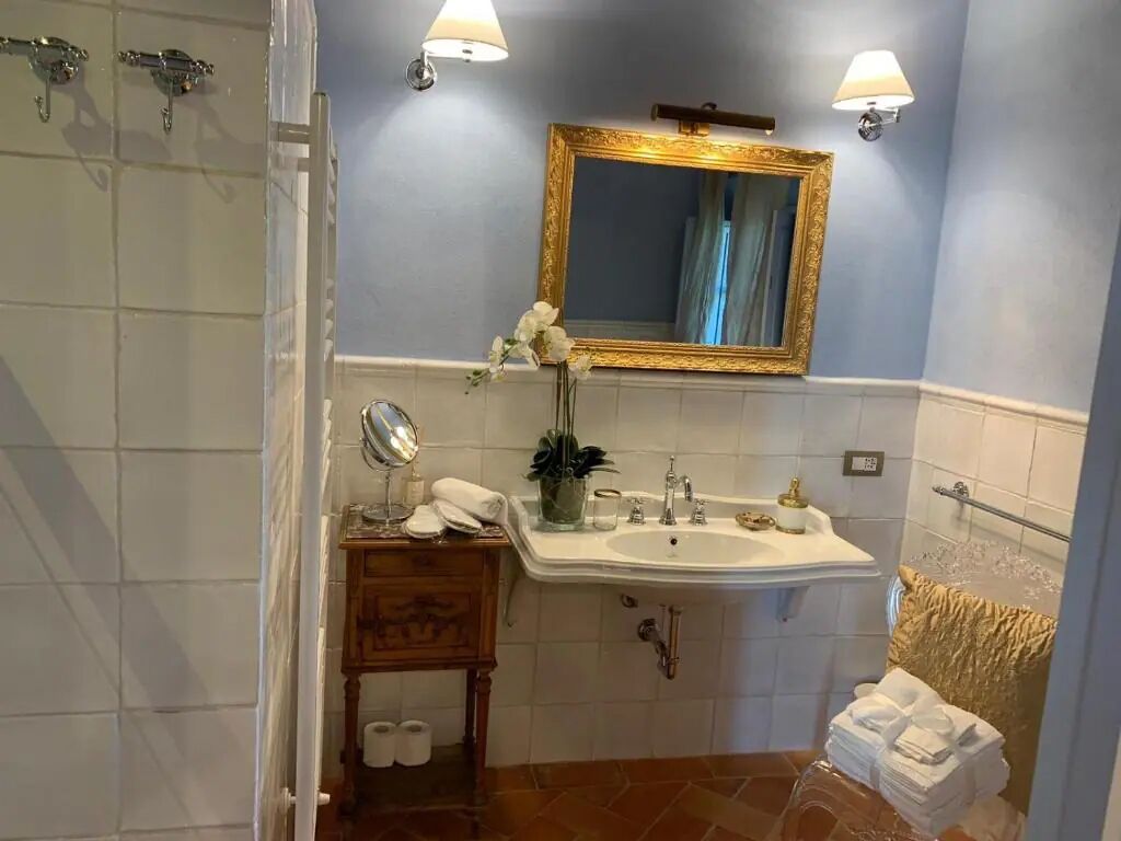 A bathroom with a sink, mirror, and shower.