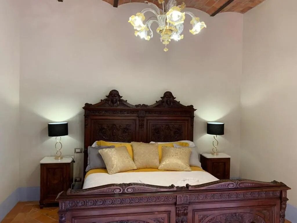 Un dormitorio con una cama de madera grande, dos mesitas de noche con lámparas y un candelabro.