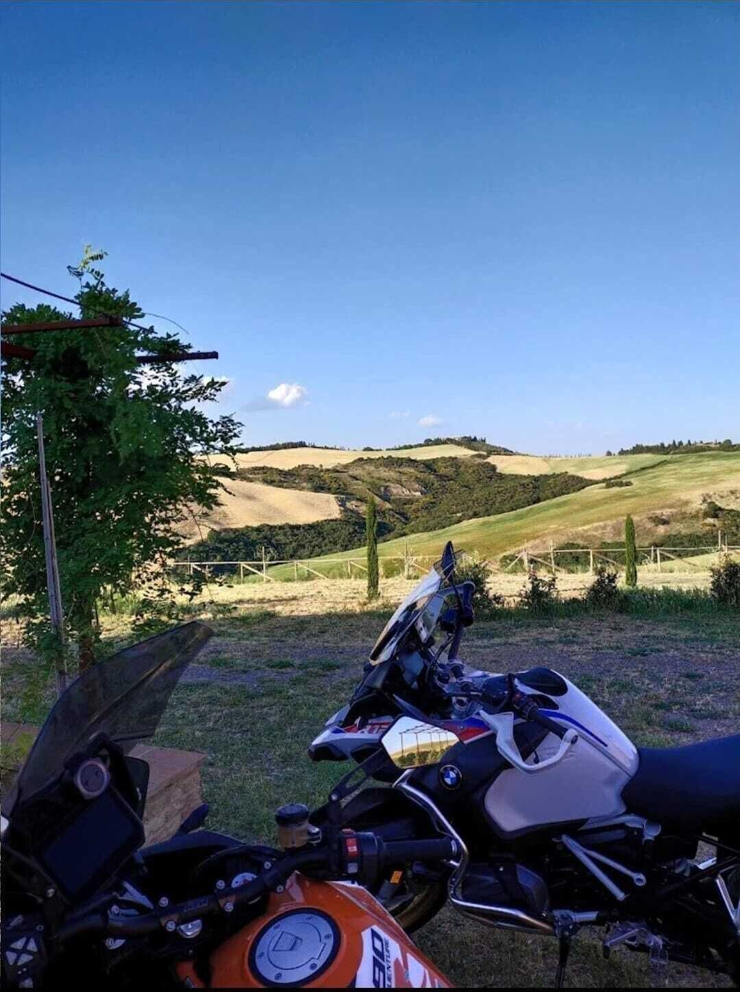 En motorcykel parkerad på en lantlig plats med böljande kullar i bakgrunden.