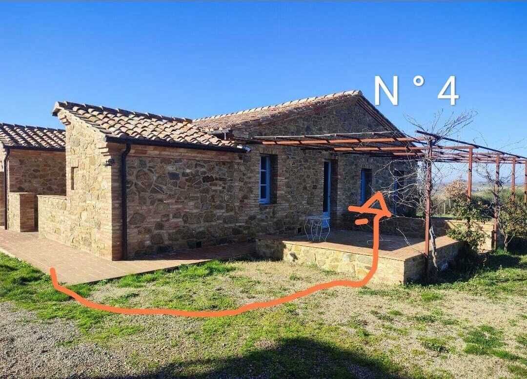A stone building with a tiled roof, a covered porch, and a clear sky.