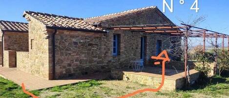 A stone building with a tiled roof, a covered porch, and a clear sky.