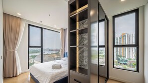 Une chambre moderne dotée d’un grand lit, d’une armoire intégrée et de grandes fenêtres offrant une vue sur la ville.