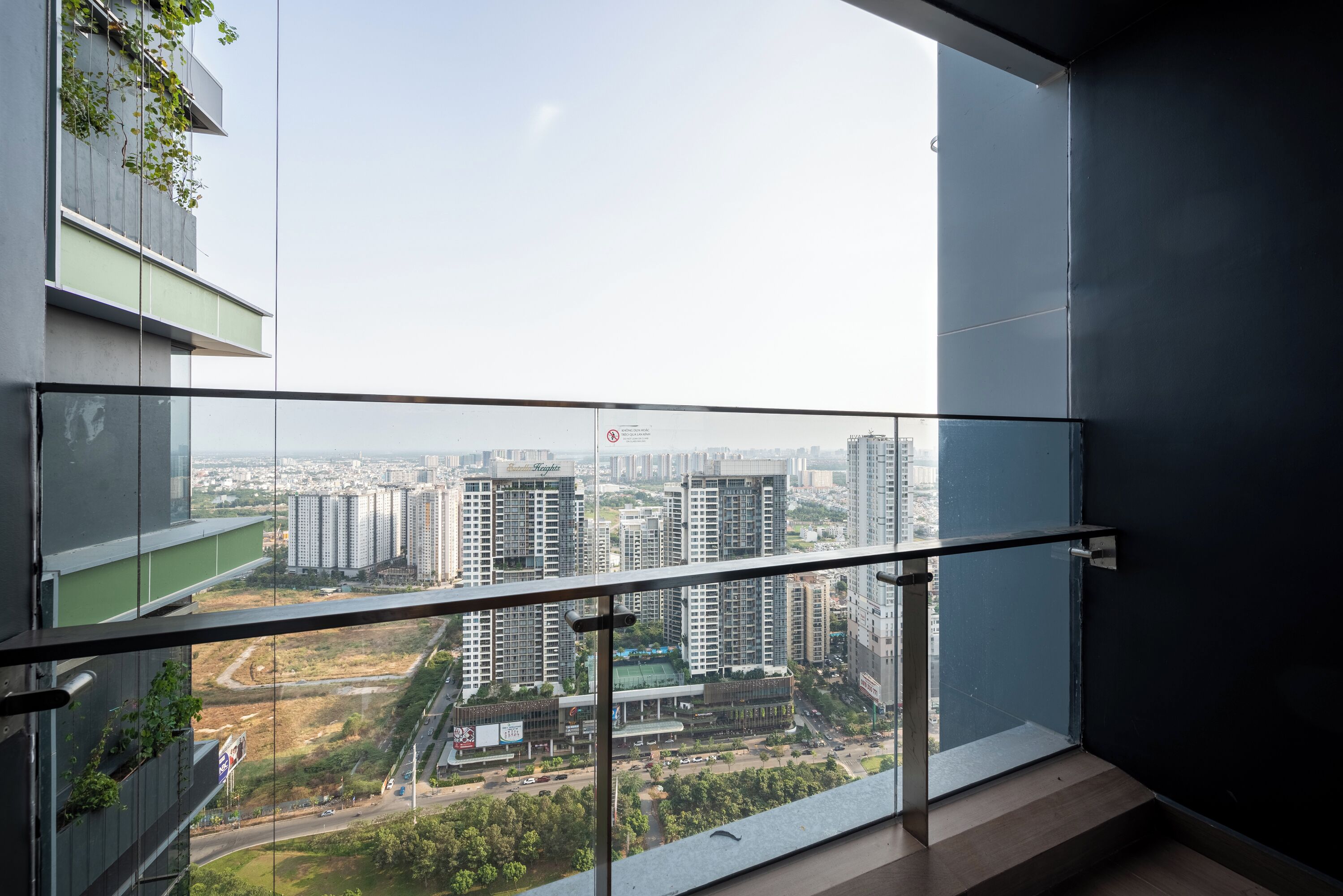 A balcony with a city view, glass railings, and a modern building facade.