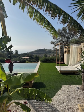A poolside area with a view of the water, a grassy lawn, and a wooden pergola with a white canopy. - Villa MAJU (Marina)