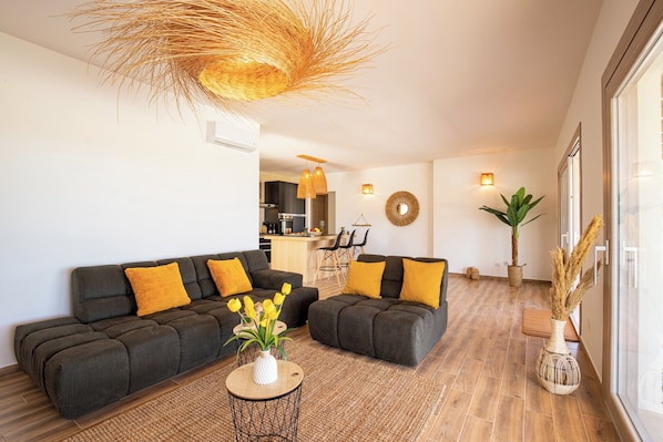 A modern living room with dark sofas, a round coffee table, and a large window.