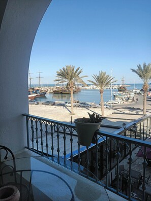 A balcony with a view of a marina, palm trees, and parked cars. - EL MANZEL 102 (HOUMT SOUK)