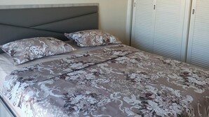 A bedroom with a bed, a headboard, a painting, and a set of closets. - EL MANZEL 102 (HOUMT SOUK)
