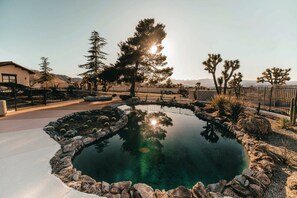 Rock-lined pool at golden hour, pines beyond