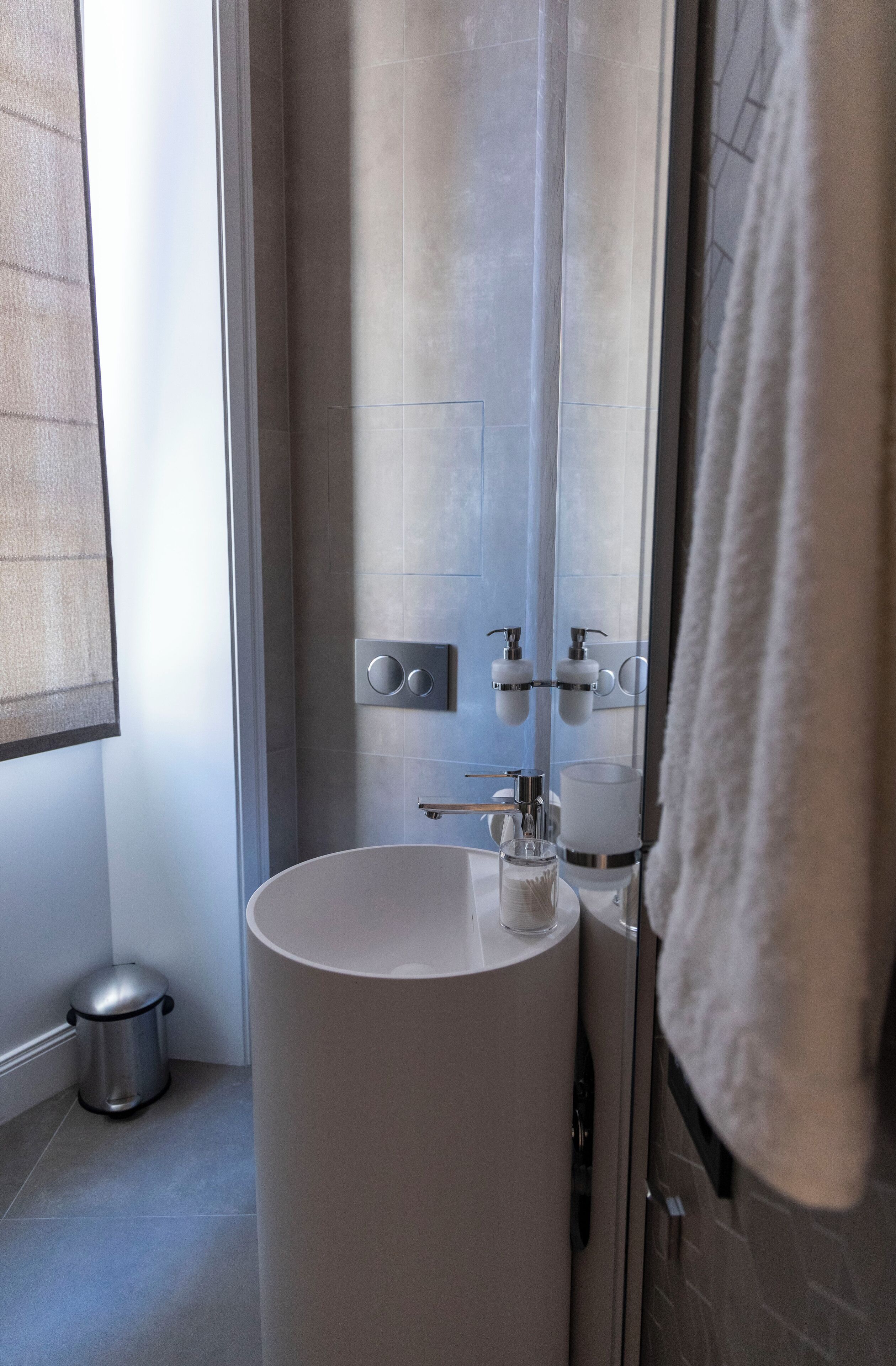A modern bathroom with a large sink, a mirror, and a shower area.