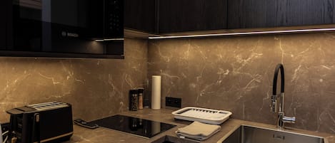 A modern kitchen with a Bosch microwave, a toaster, a sink, and a marble countertop.