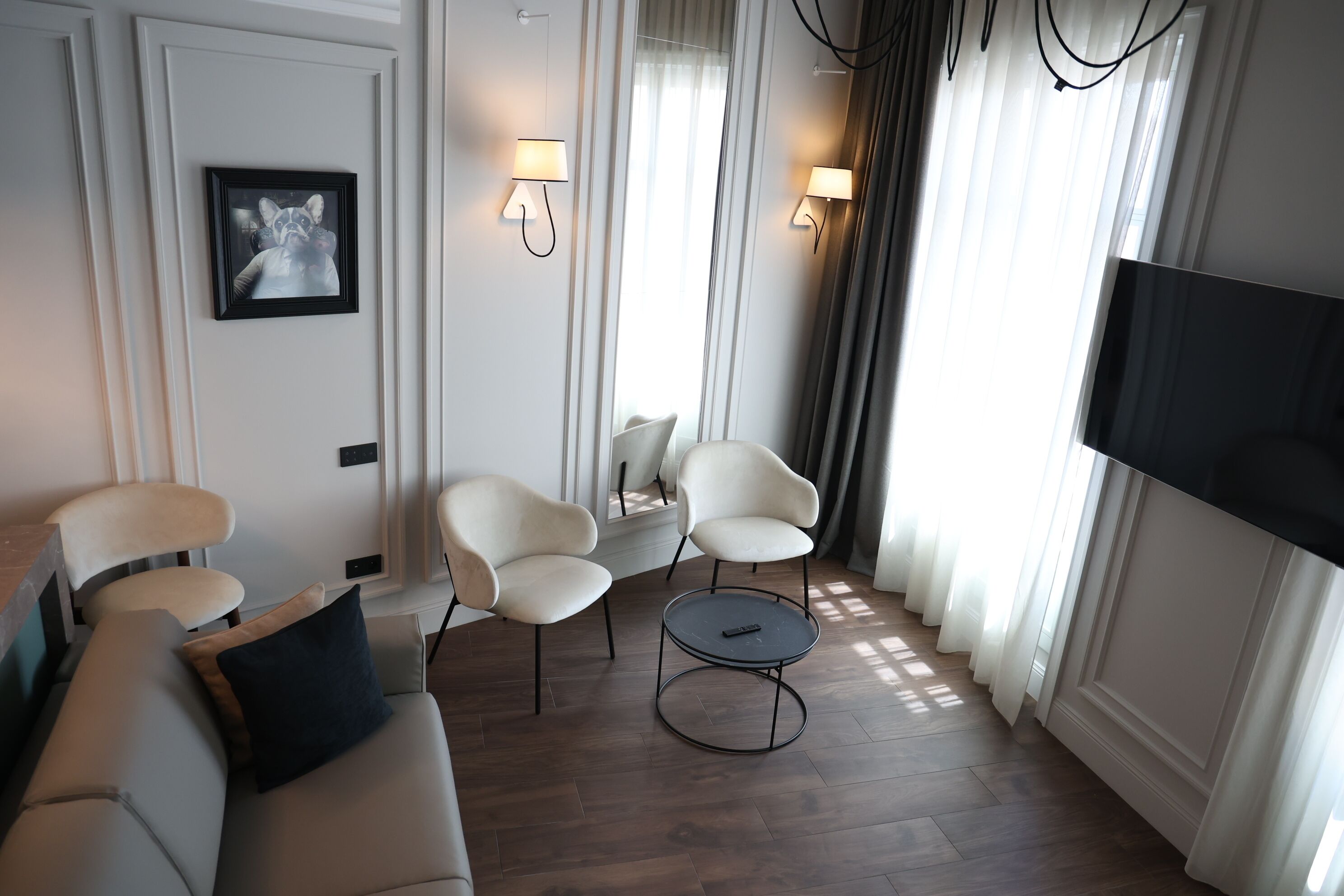 Ein modernes Wohnzimmer mit einer Couch, zwei Sesseln, einem runden Couchtisch und einem an der Wand befestigten Flachbildfernseher.