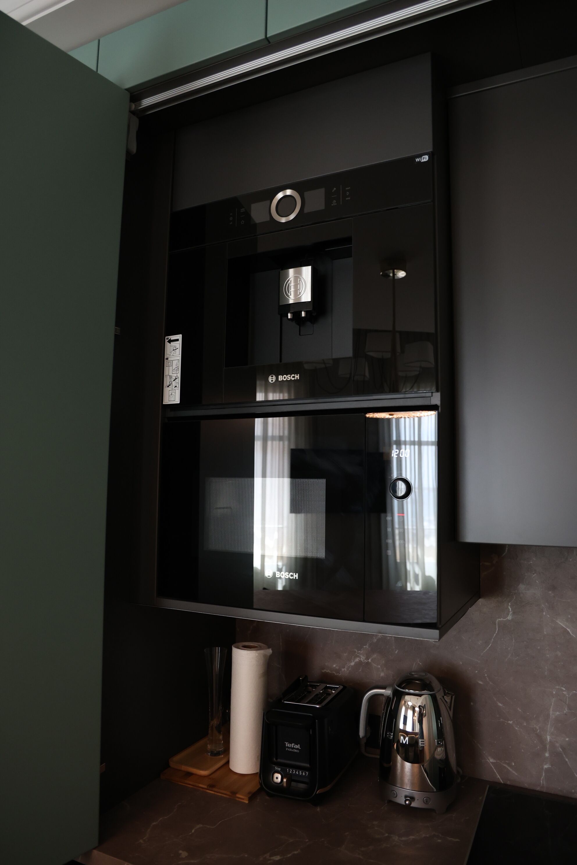 A kitchen with a Bosch refrigerator, a toaster, and a kettle on the counter.