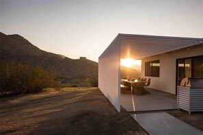 Situated in a serene natural setting, this modern building offers a patio area perfect for outdoor dining or social gatherings.