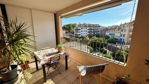 Un balcon avec une table et des chaises, des plantes en pot et une vue sur les bâtiments.
