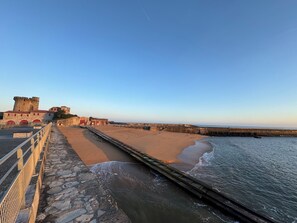 Access the coastal fort through a sandy beach via a wooden walkway.
