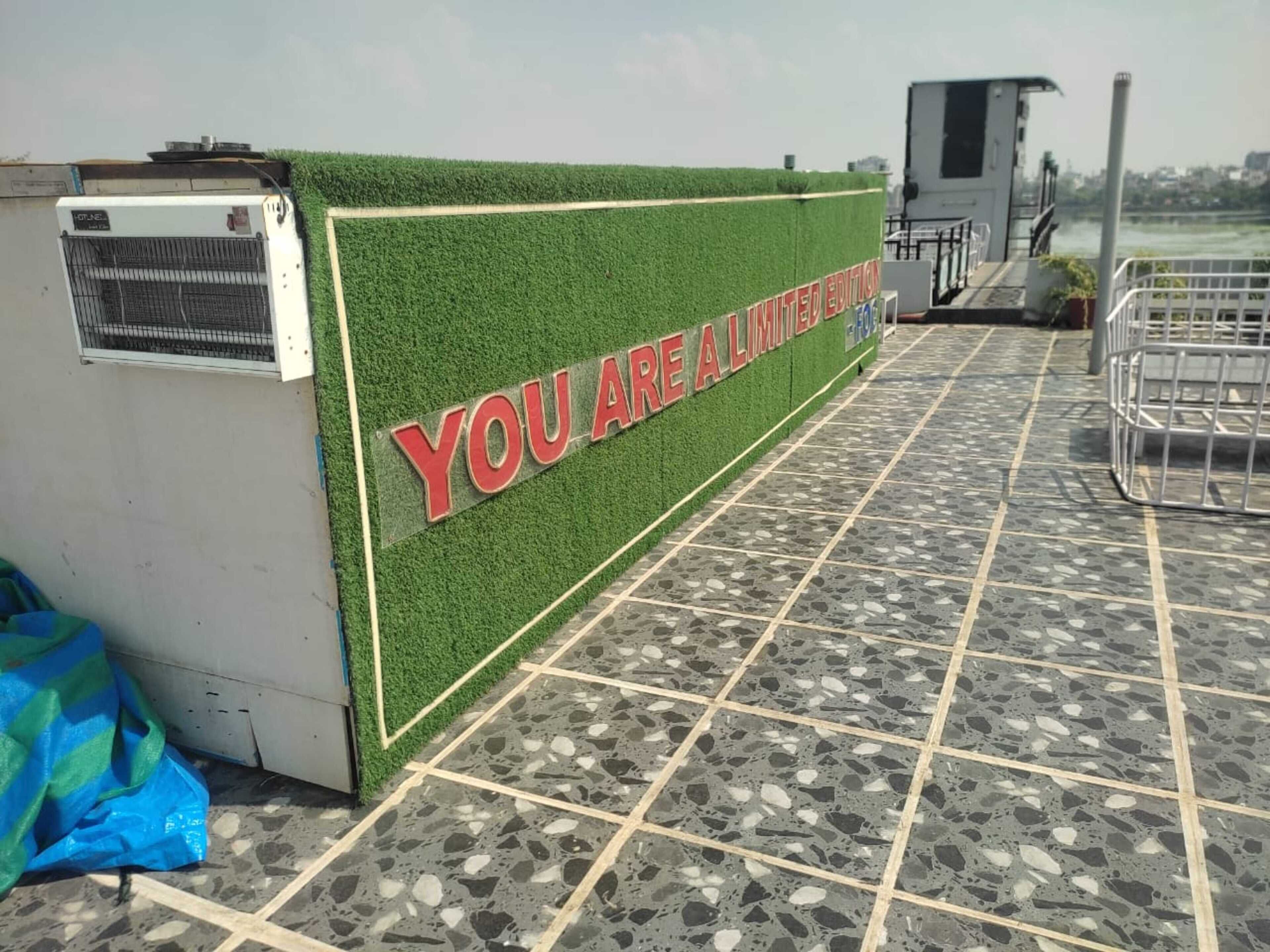 Mostrador de recepción con fondo de césped artificial verde y un cartel que dice 'YOU ARE A LIMITED EDITION'.