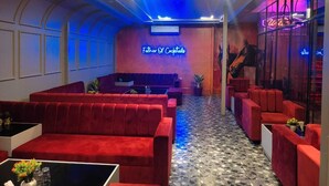 A modern lounge area with red sofas, a neon sign reading "Father of Cool," and a large window with a view. - Hotel Wonder View By GRB Stays (Kota)