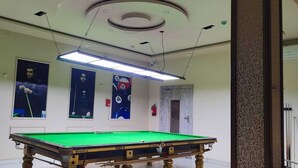 A billiards room with a pool table, ceiling lights, and posters on the walls. - Hotel Wonder View By GRB Stays (Kota)