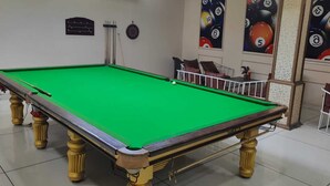 A pool table with a green felt surface, surrounded by white chairs and cushions. - Hotel Wonder View By GRB Stays (Kota)