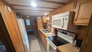 Cocina compacta con armarios de madera, microondas, horno y lavamanos.